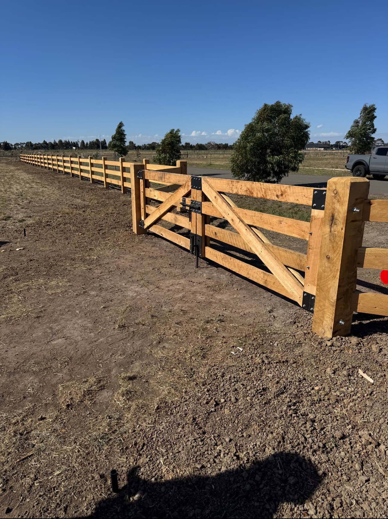 Cypress post and rail fence with matching double gates on an acreage property